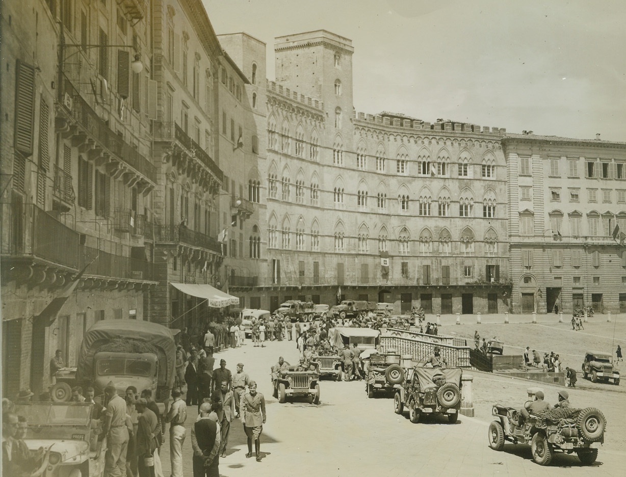 ALLIED TROOPS ENTER SIENA, 7/9/1944. ITALY—Jeeps roll through the street in the town square of historic Siena, one of the foremost art centers in Italy and the most perfectly preserved of the medieval cities on the Italian peninsula. Town was taken by French troops of the Fifth Army placing Allied forces only 25 miles from Florence. Note that the square is devoid of damage. Proof the the rapidity with which the Nazis are fleeing before the might of Allied forces in Italy. Bitter fighting is now raging in the rolling hills above Siena. Credit: Acme photo by Charles Seawood, War Pool Correspondent;