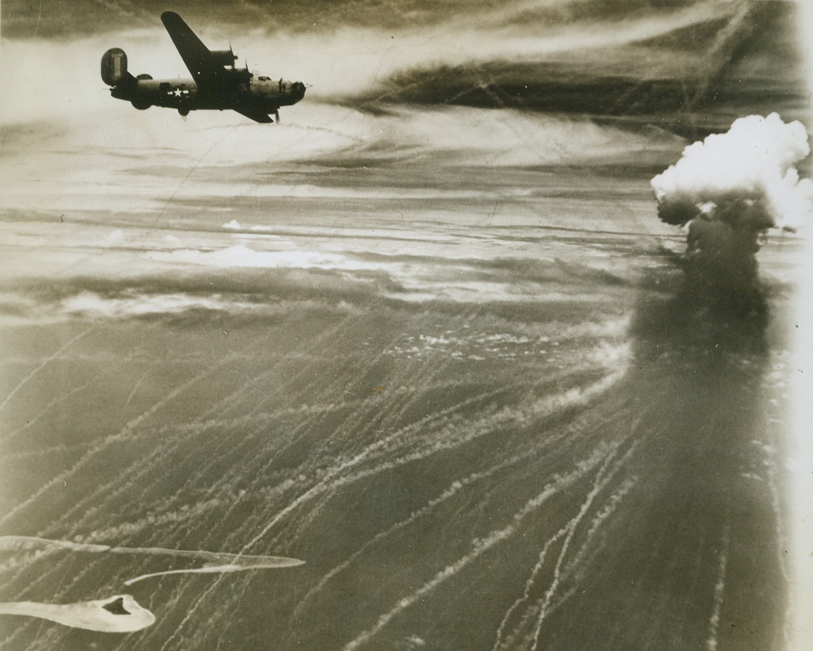 Flying Through Phosphorus, 7/21/1944. Truk – Its bomb load delivered to Truk (lower left), which is now under constant attack, a Liberator heads homeward through a phosphorus-filled sky. One of the phosphorus bombs, dropped by Jap planes at least 1000 feet above the B-24, explodes at right. Credit: U.S. 7th Air Force photo from ACME;