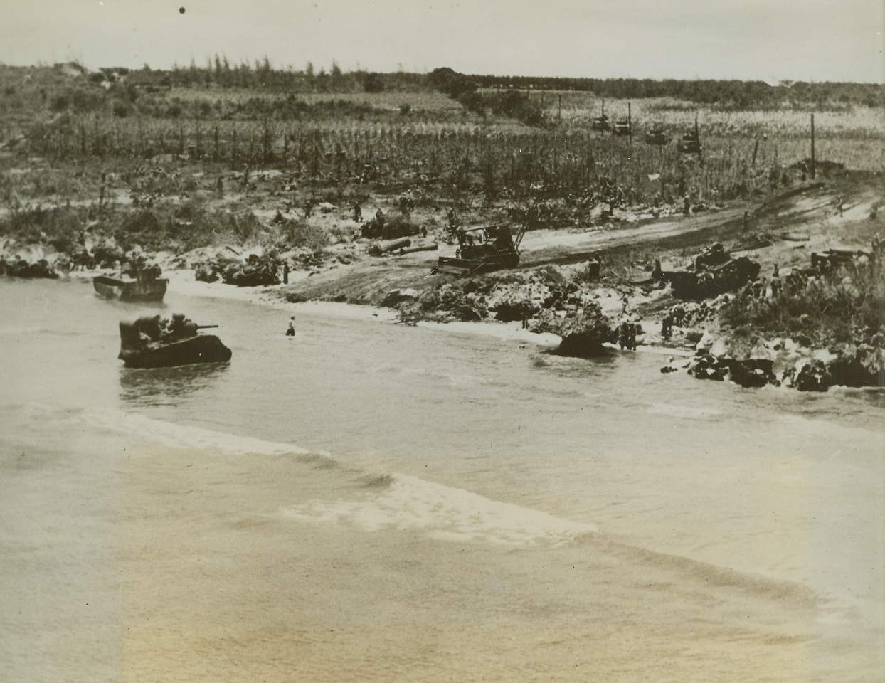 Marines Push Forward on Tinian, 7/28/1944. , Marianas Is. – With monotonous regularity – for the Japanese on the Marianas Islands – the Marines land again. This time it is Tinian, less than three miles from Saipan, and the third in the group to be invaded in less than six weeks. Tanks roar ashore from landing craft, drive up beach road gouged out by a bulldozer toward island’s vital airfields.Credit line Marine Corps Photo from ACME;