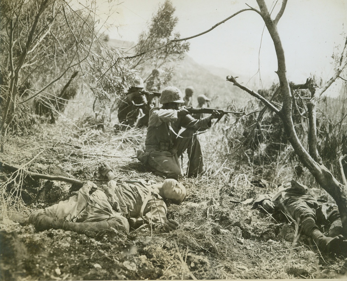 The Quick Heed not the Dead, 7/21/1944. Saipan - - Unmindful of the bodies of enemy soldiers lying close to them, Marine fighters kneel and take aim as they push ahead through Saipan.  Members of the Second Marine Division, the warriors are making their way toward the Western beach below Mt. Marpi.;
