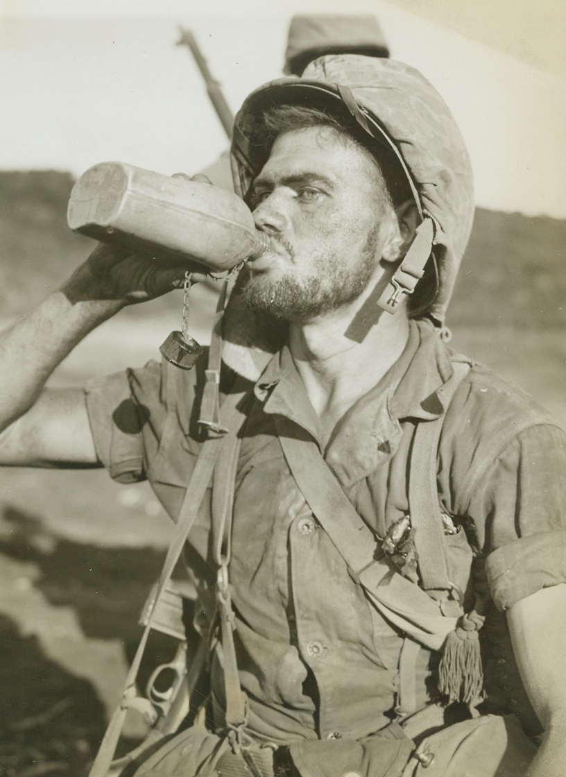 Thirsty Leatherneck, 7/21/1944. Saipan – Hot and weary after fighting on the Western beaches below Saipan’s Mt. Marpi, Marine Pfc. T.E. Underwood of St. Petersburg, Fla., takes a long, cool drink of water from his canteen. Beads of perspiration glisten on the weary Leatherneck’s unshaven face. Credit line –WP- (ACME photo by Stanley Troutman for the War Picture Pool);