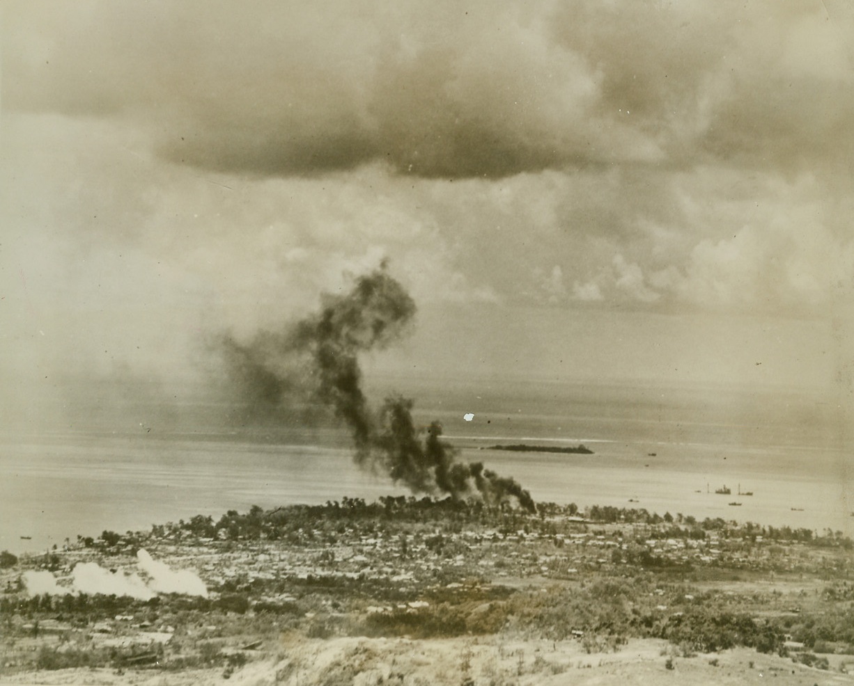 Warships Shell Garapan, 7/5/1944. Garapan, Saipan – Leathernecks from the Second Marine division – the conquerors of Tarawa – were tightening the vise around the city of Garapan, capital of Saipan, when this photo was taken.  Fires in the coastal area were caused by fleet bombardment and sunken Japanese shipping can be seen in the harbor.  Garapan has surrendered and is now in American hands. Credit line (Coast Guard photo from ACME);