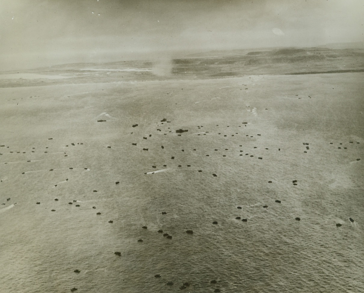 Tinian Invasion Gets Under Way, 7/30/1944. Tinian, Mariana Is. – As smoke rises from pre-invasion artillery pounding on Tinian, waves of small landing boats head for the beach as Marines begin their invasion of the island.  This was the third island of the Marianas to be invaded by US forces within 6 weeks. Credit (Marine Corps photo from ACME);