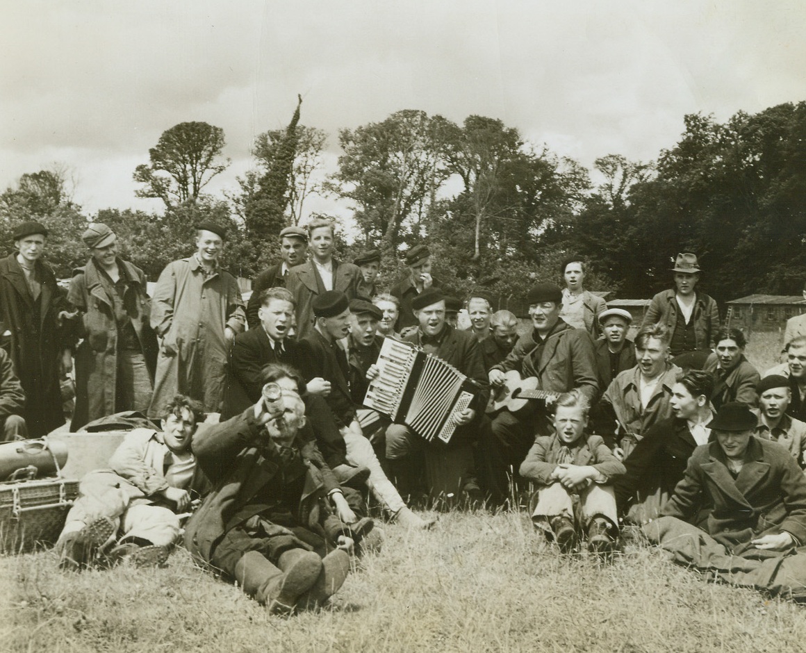 Freed Russians to Return to Homeland, 7/10/1944. Normandy, France—This hilarious group of Russians, freed by the Allies from their enforced labor with the German army, celebrate their liberation in the traditional way—wine and song (their women are waiting for them back in Russia). They are waiting in an Allied camp for transportation to England and from there to Russia. Credit: ACME photo by Andrew Lopez, War Pool Correspondent.;