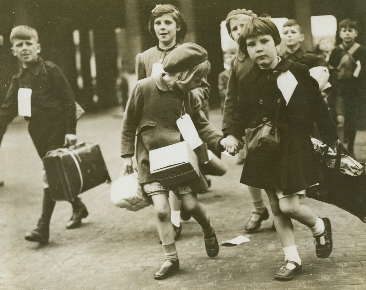 Evacuate London Children, 7/12/1944. LONDON - London authorities are continuing the evacuation of children from the city limits to get them away from the indiscriminate shelling by the Nazi robot bombs. Recently hundreds left for safer areas in the midlands and north England. Carrying parcels , little evacuees bound for the countr walk toward their train.;