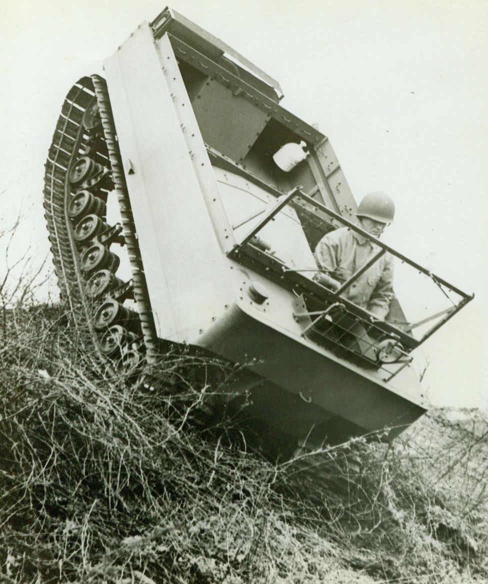 Weasel Joins the Army Parade, 7/3/1944. SOUTH BEND, IND. - In secret production for two years at the Studebaker Automobile Factory in South Bend, Ind., a radical war vehicle is shown for the first time by the Army. Known as the "Weasel" (official name is M-29) it is a low-slung, square-faced  personnel and supply carrier, capable of operating over snow, deep mud, sand or on paved highways, a greater variety of terrain conditions than possible in any other previous vehicle. The Weasel's light weight combined with broad rubber-padded tracks allow for high speeds on any ground condition. Pressure on the ground exerted by the Weasel is about One-Fourth that of a fully equipped infantryman. The Weasel, minus its camoflage and canvas curtain top for summer use, negotiates a steep grade with ease.;