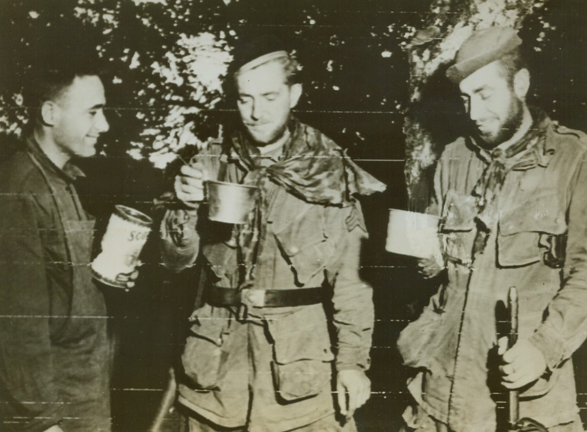 END OF 37 FOODLESS DAYS, 7/18/1944. FRANCE—Pvt. John C. Rodrigues, Pawtucket, R.I. (left), gives paratroopers Sgt. R.D. Henderson, Seattle, Wash., and Sgt. H.W. Lazenby, Nashville, Tenn., (right) their first food in 37 days after their capture by Germans on D-Day. The ‘troopers escaped and made their way back to Yank lines. Credit (US Army Radiotelephoto from ACME);