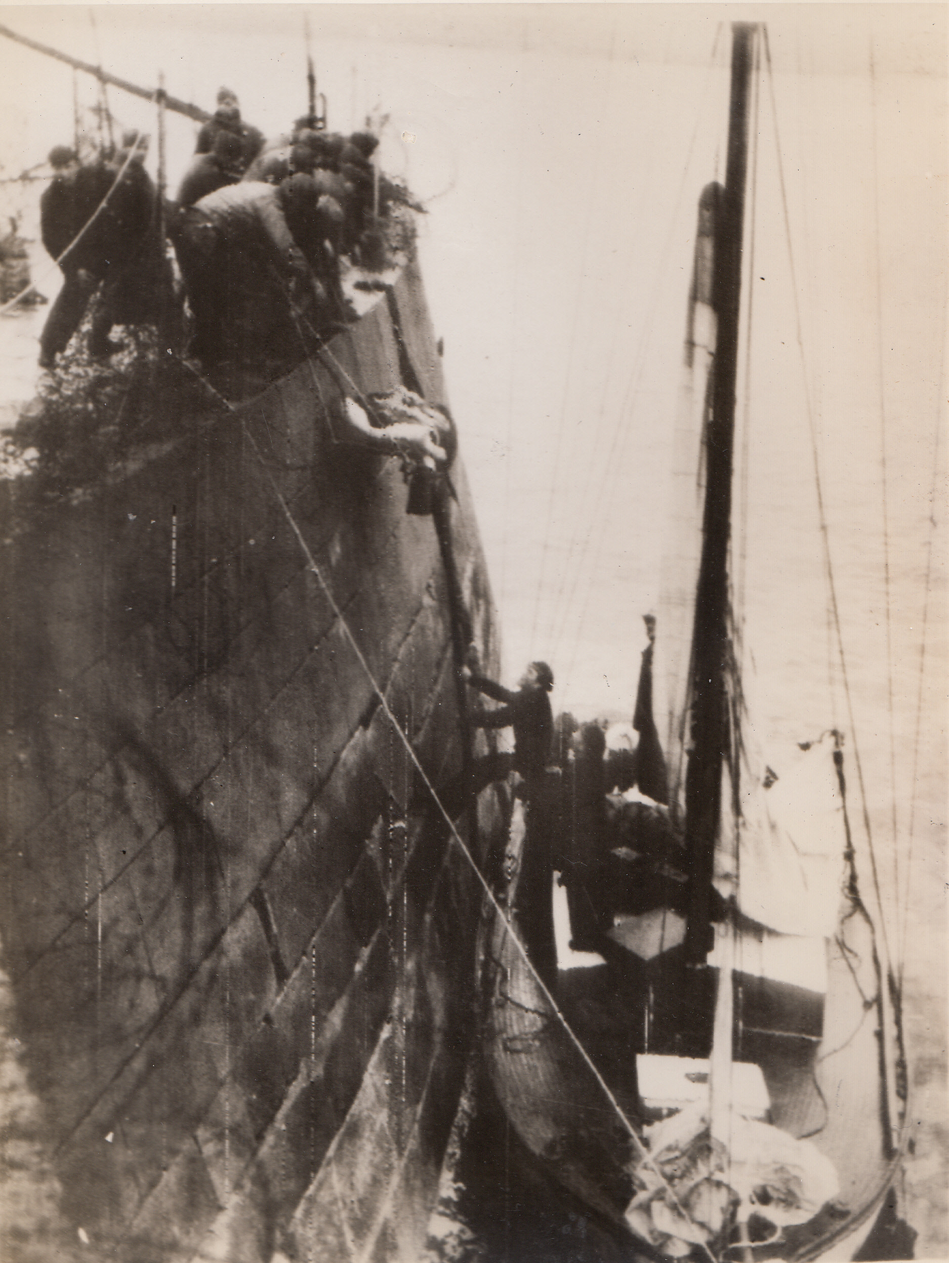 He Guarded The Harbor, 7/3/1944. Cherbourg, France – A sailor stands in the sailboat waiting to receive the stretcher on which is a wounded German non-com. He is being evacuated from a Cherbourg Harbor fort, where he was stationed at the time the American forces invaded the port city.;