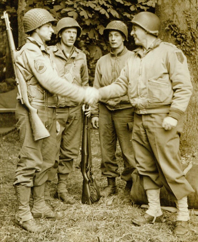 Held French Town for Two Days, 7/9/1944. France— Maj. Gen. Clarence R. Huebner, of Washington, D.C., Commanding the first American Division in Normandy, congratulates (Left to Right); Sgt. Stephen Sternik, Johnson City, N.Y.; Fraut Baldridge, Quitman, Ark.; and Lt. Kenneth Bleau, of Ilion, N.Y. The three men entered the little French town of Colleyville-Sur-Mer on D-Day and throughout that night and the next day held their position killing 100 Germans during the action. They were eventually relieved by their comrades of the First Division. The amazing story of their heroic action has just been disclosed and the men have been recommended for decorations 7/9/44 (ACME);