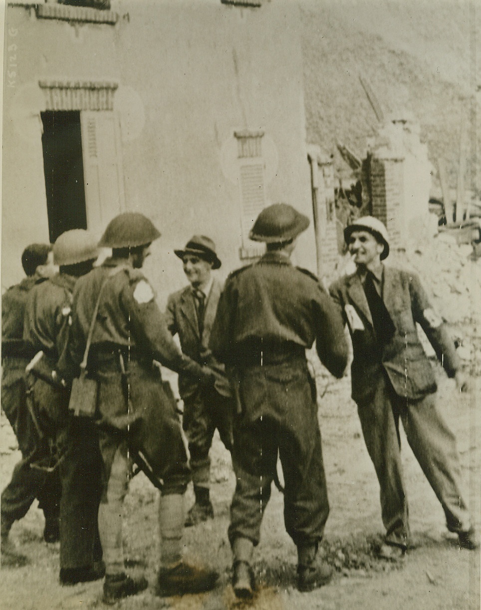 Hearty Welcome to Caen, 7/11/1944. France—With broad smiles on their faces, Capt. Gille (left), President of the Calvados Committee for Liberation, and M. Dauvre (right), Prefect of Calvados, (both men facing camera), rush forward to welcome the first British troops to enter Caen. Credit: Army radiotelephoto from ACME;