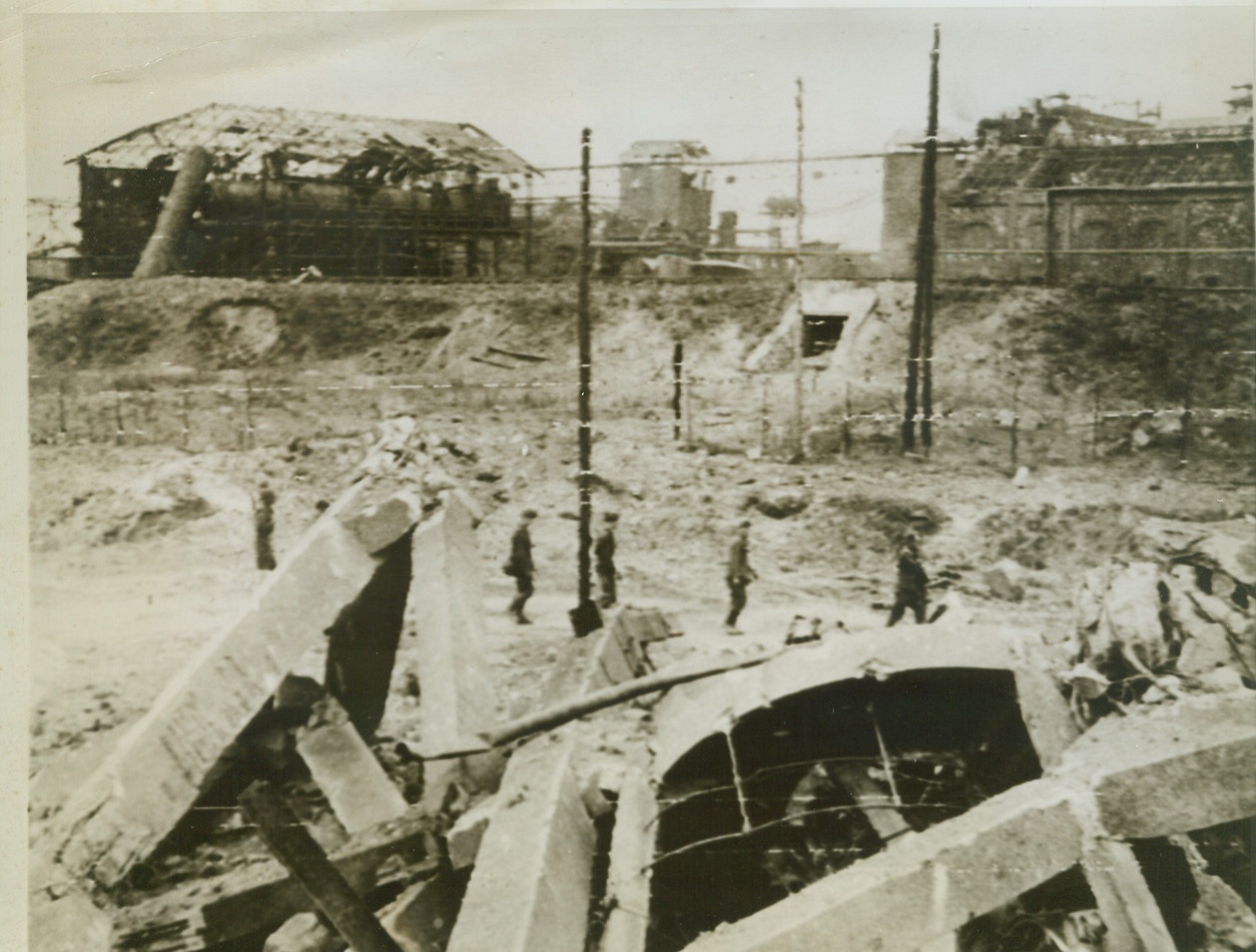 Nazi Prisoners and Desolation, 7/21/1944.France—Captured in the great Allied break-through beyond Caen, Nazi prisoners file dejectedly past the ruins of a water tower that was part of a factory in the industrial area outside Caen. Entire area is a mass of ruins as a result of the awesome artillery barrages that swept the territory. Credit: British war office photo via Signal Corps radiotelephoto from ACME;