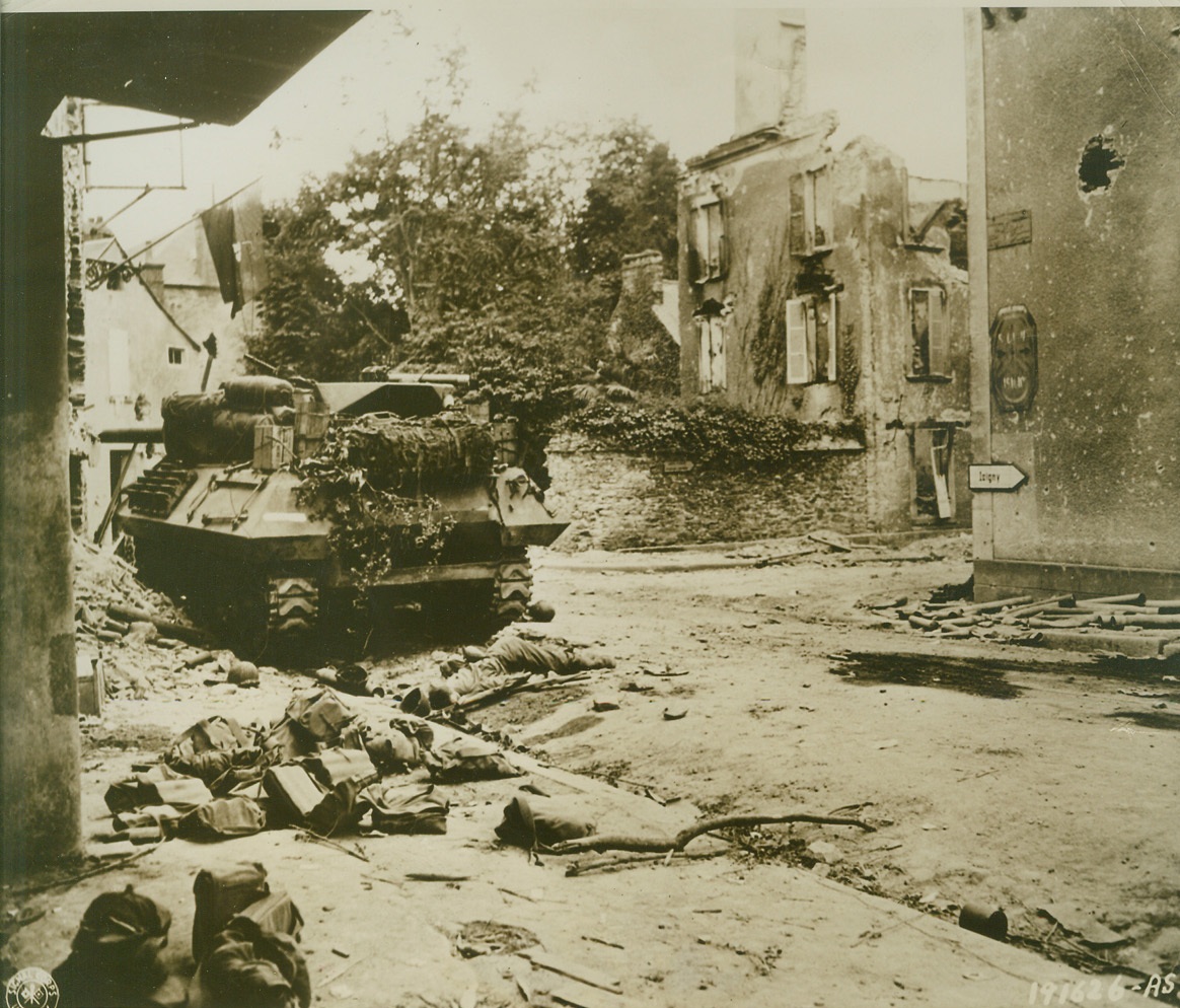 Price of Victory, 7/25/1944. St. Lo, France—A knocked out American tank destroyer, with the body of a dead Yank lying in the road behind it, marks this crossroad in St. Lo, after U.S. forces entered the town. Credit: U.S. Army photo from ACME;