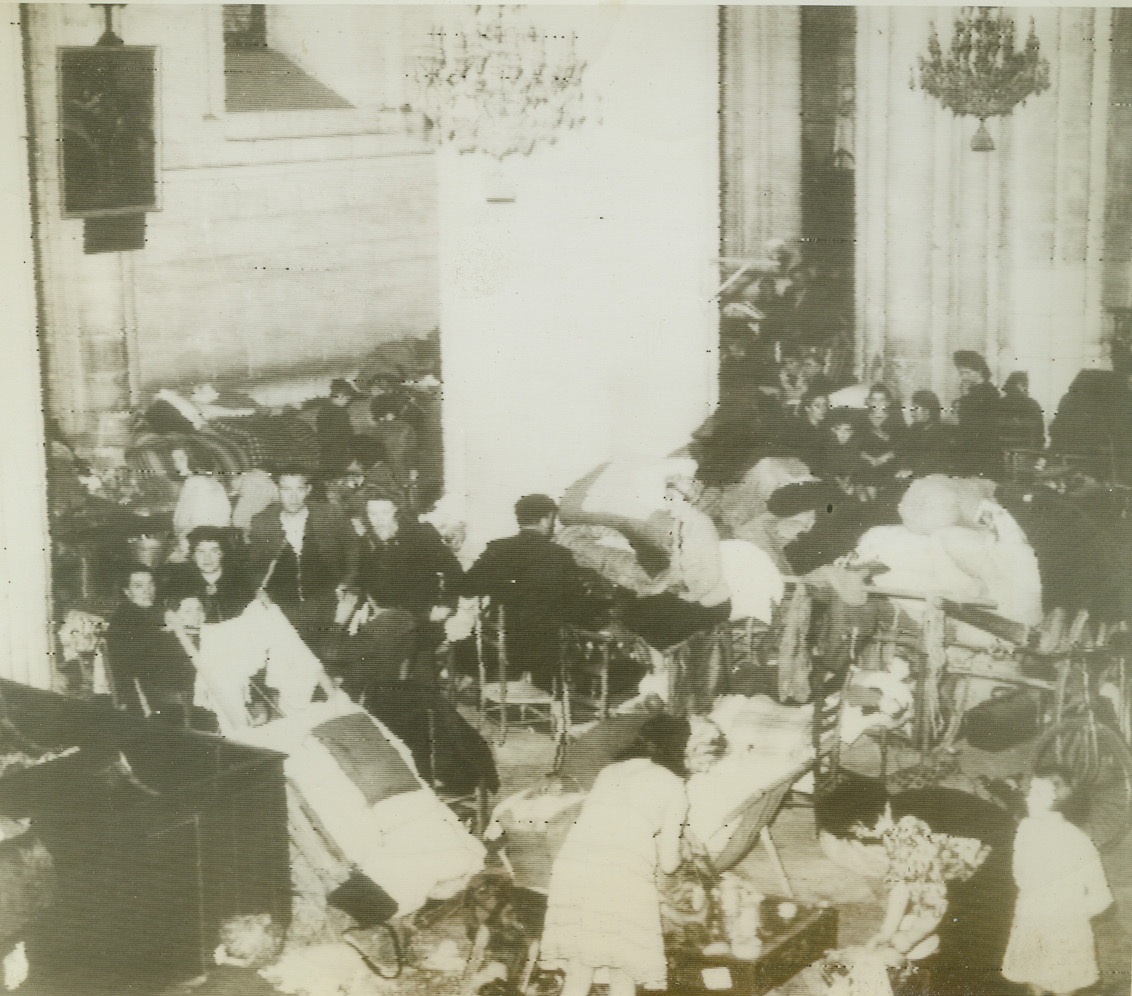 French Refugees Sheltered by Allies, 7/15/1944. Caen, France—Crowded into a cathedral when the British and Canadian forces captured Caen, hundreds of French refugees lived, ate, and slept within their hallowed confines. Now, with mopping-up operations of the city completed, the refugees are being slowly evacuated under Allies care, and those whose homes have been destroyed, will be given shelter elsewhere. Credit: British official radiotelephoto from ACME;