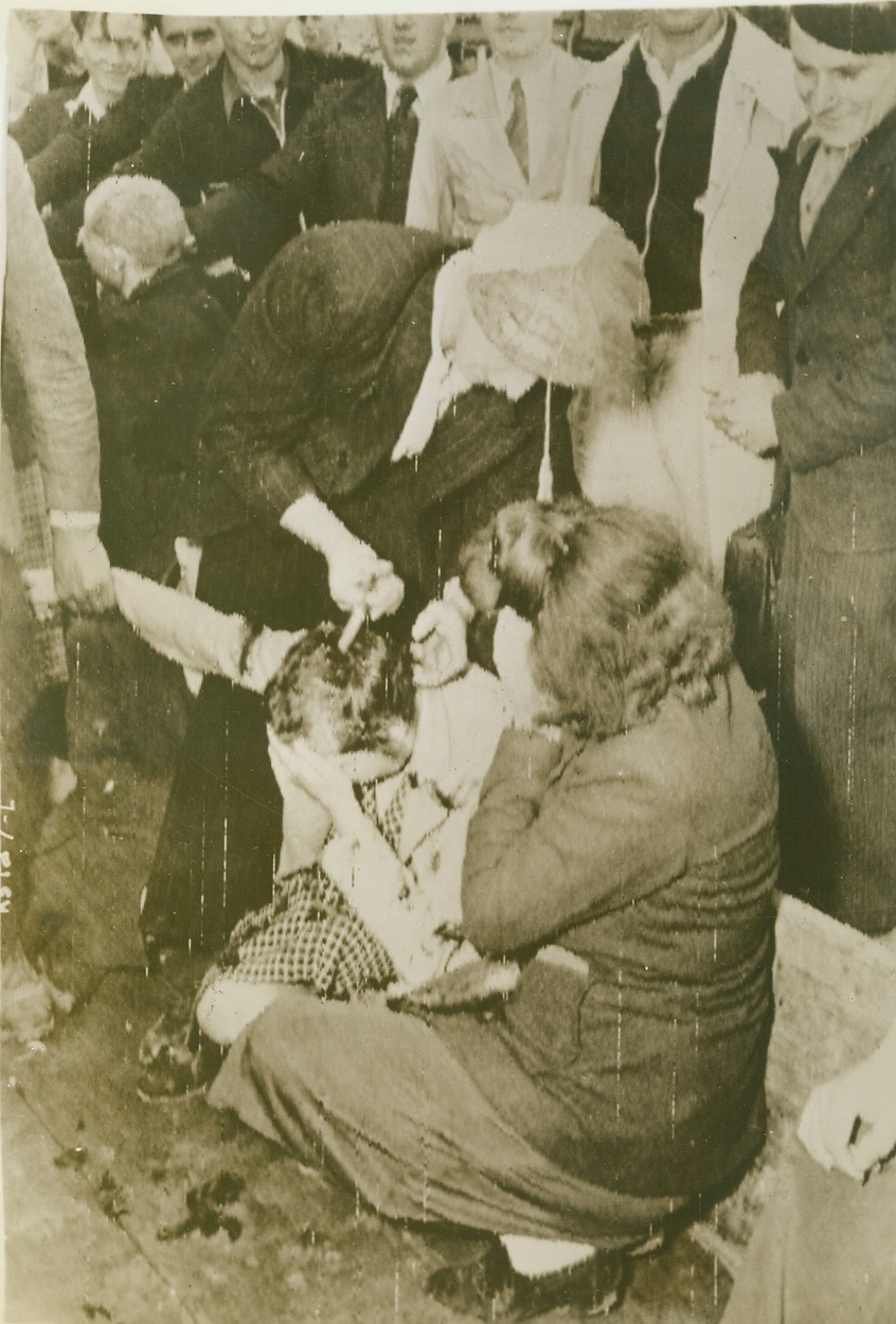 So That All May Know Her Shame, 7/16/1944. Cherbourg, France—Known to have collaborated with the Axis during German rule in Normandy, this Frenchwoman pays the price required of all female friends of the Boche. While loyal natives gather around, one patriot shears the hair from the girl’s head. With other collaborationists, she was later paraded around the streets of Cherbourg.  Credit: Signal Corps radiotelephoto from ACME;