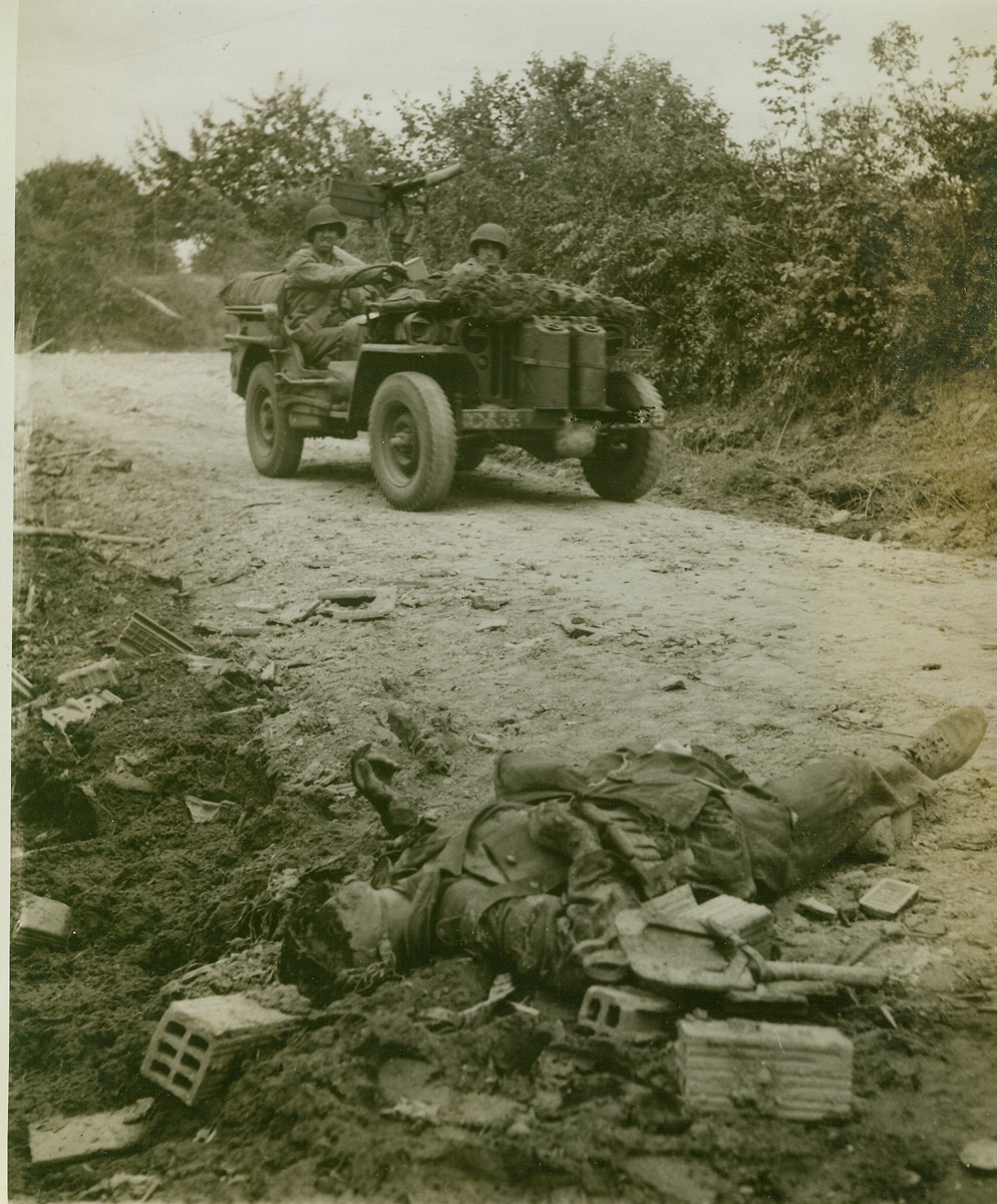 . . . And Sudden Death, 7/16/1944. Normandy—Death came swiftly and violently to this German tanker, who tried in vain to escape when his tank was trapped in the “Lane of Death” in the sector between St. Jean de Dye and St. Lo. His shattered remains lie at the side of a narrow road where 7 tanks, a 46-ton Tiger tank, a number of radio cars, and other German armor were knocked out of the fight. Credit: ACME photo by Bert Brandt, for the War Picture Pool;