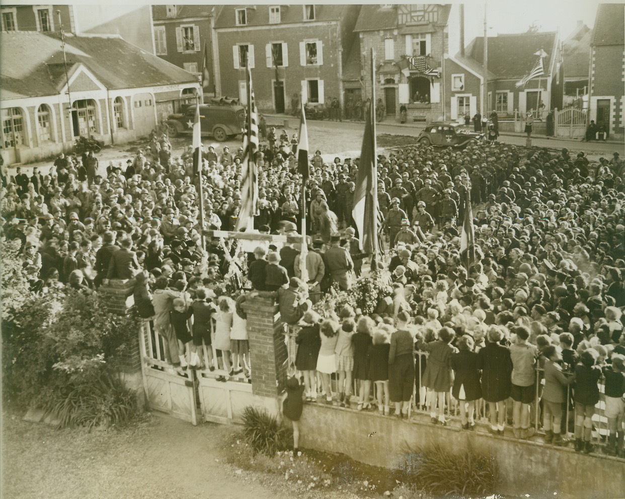 And Little Children Line The Rail, 7/9/1944. France—A huge crowd of 1600 residents of Grandcamp, Little Normandy town, gathered in the main square to help Yank troops of occupation celebrate Independence Day. It was a day of independence for the French inhabitants also. Suffering under the heel of the ruthless Nazis for four years, Grandcamp is grateful to the Americans who liberated them. Town was the first freed by the Yanks. Note the little children lined on the rail anxious to see the celebration.  Credit: ACME photo by Bert Brandt, War Pool Correspondent;