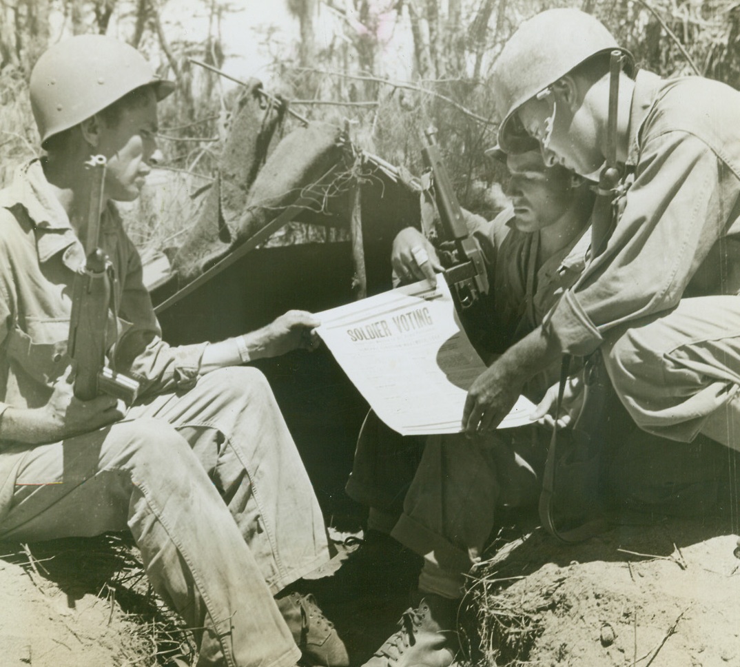 POLITICS ON THE BATTLE FRONT, 8/11/1944. NEW GUINEA—Yanks in New Guinea, near the battle lines down the Driniumor River near Aitare on New Guinea, study requirements for soldier absentee ballot. They are (left to right): Pfc. Leonard C. Layton, Dayton, O.; Cpl. Henry Betley, Barron, Wis.; and Pfc. Andrew Rothstein, New York City, all members of a headquarters company. Credit-WP (ACME Photo by Tom Shafer, War Pool Correspondent);