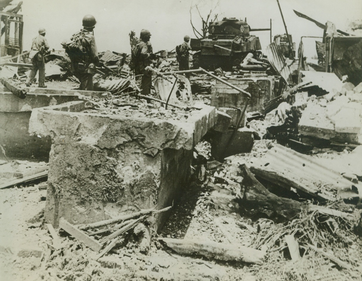 Leathernecks Enter Former Marine Barracks, 8/6/1944. Guam – US Marines hold their guns cocked as they look for signs of Japs hiding amidst the ruins of the old Marine barracks on Guam. Moving in without opposition, they are the first men and tanks to enter the site, which has been almost completely destroyed by aerial and naval bombardment. Credit (ACME);