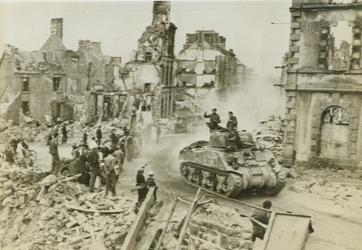 Enroute to Pincer the Germans, 8/20/1944. Flers, France -- Townspeople in the bomb-wrecked, shell-ridden town of Flers line the streets to cheer British soldiers who move on in their “General Sherman” tanks to close the gap at Falaise and trap the German forces fleeing toward Paris. This is a British War Office photo. Credit: US Army photo from ACME;