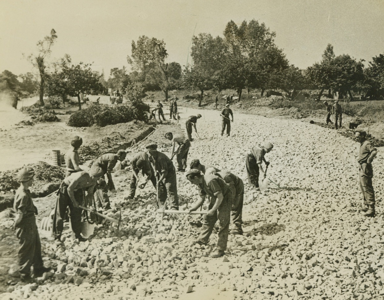 TO KEEP ‘EM ROLLING, 8/15/1944. FRANCE – British Royal Engineers, using stone from damaged buildings and flint limestone from the stock of a former German factory near Colombelles, repair a stretch of road near that city. Credit: British official photo from Acme;