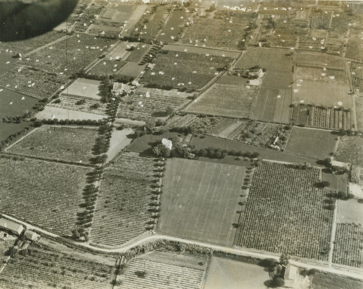 -- Left Their Tails Behind Them, 8/19/1944. Southern France – Parachutes dot the flat terrain of southern France after the early morning landings on August 15, when Allies staged a surprise airborne invasion. Soldiers quickly abandoned their ‘chutes and set out to mop up enemy resistance. Credit: ACME photo by Charles Seawood, War Pool Correspondent;