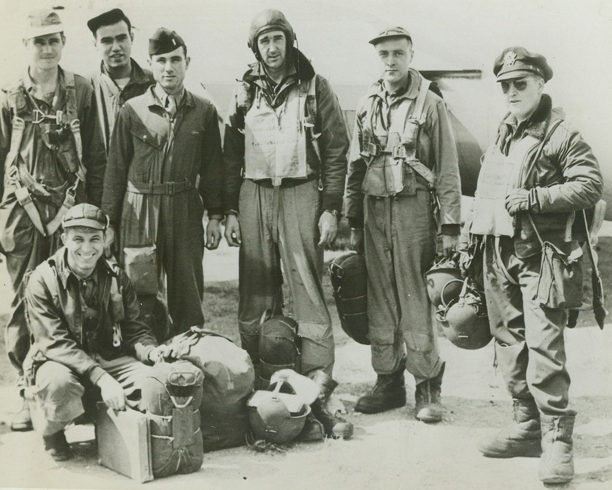 Back from Raid on Alsace Lorraine, 8/22/1944. England – American airmen return to their base in England after raiding targets in Alsace Lorraine. They are (left to right): S/Sgt. Henry L. Wolf, Coahoma, Texas; Sgt. Burdette E. Bonner, Galesburg, Illinois; S/Sgt. Robert B. Linnemann (stooping), Cincinnati, Ohio; 2nd Lt. Burnett L. Deyerle, Roanoke, Virginia; Joseph R. Lyons, Wooster, Massachusetts; 2nd Lt. Lorne R. Marlatt, Brooklyn, New York; and 1st Lt. Neil A. Daniels, Oak Park, Illinois. Credit: ACME;