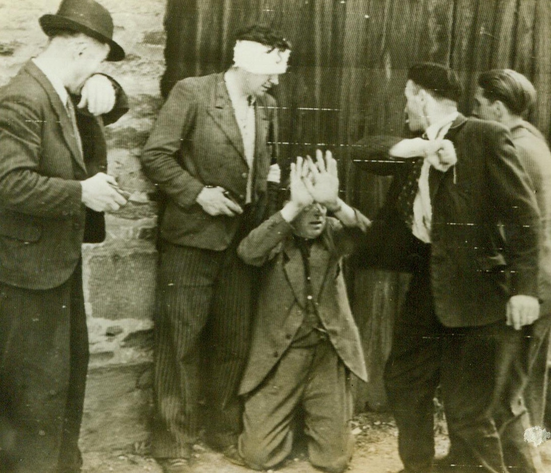 Collaborator Gets His Lumps, 8/6/1944. Rennes, France --Seeking vengeance from the disloyal in their midst, French patriots were quick to round up traitors and mete out punishment when Rennes fell to Allied forces. Here a kneeling collaborationist holds up his hands to fend off blows delivered by enraged patriots 8/6/44 (ACME);