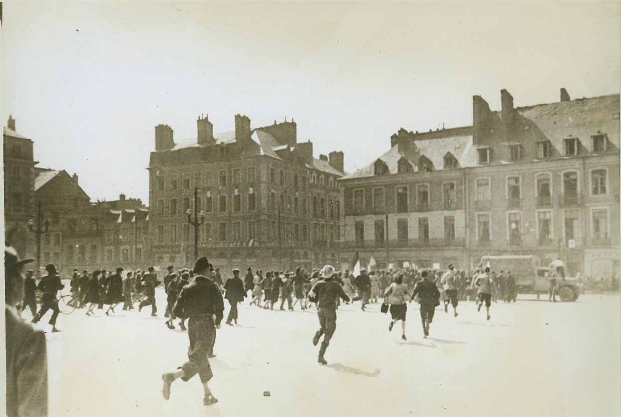 Collaborator Spotted, 8/12/1944. RENNES, FRANCE -- Citizens of Rennes, their liberation by the Allies in the town square, spot a collaborator about to be put into a captured truck on the other side of the square. Eager to get their hands on one of their people who betrayed them to the Nazis, they rush madly across the open space to catch the traitor. Credit (ACME) (WP);