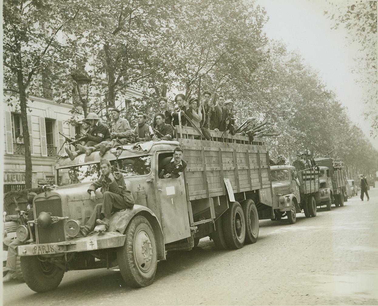 Sniper Hunt, 8/28/1944. PARIS -- Scanning streets and rooftops, FFI warriors ride through Paris in captured German vehicles, hunting German snipers and French Fascists fighting last-ditch resistance in the French capital. Note the Cross of Lorraine painted on the bumper of the captured truck in foreground. Credit: - WP- (ACME Photo by Andy Lopez for the War Picture Pool);