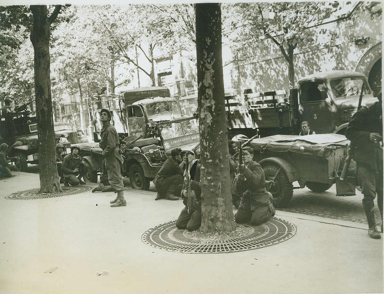 Snipers Above, 8/28/1944. PARIS -- Eyes on a rooftop where an enemy sniper has been spotted, men of the FFI and the Second French Armored Division are ready to let 'em have it during street fighting in the heart of Paris. Behind the valiant patriots are German trucks that were captured by the Maquis. Credit:-WP-(ACME Photo by Andy Lopez for the War Picture Pool);