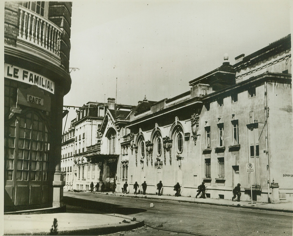 Step-by-Step Advance, 8/21/1944. Dinard, France—Hugging the wall of the casino building in Dinard, American infantrymen crouch as they advance. Making their slow way up the street, the Yanks are wary of German sniper fire.  Credit: Signal Corps photo from ACME;