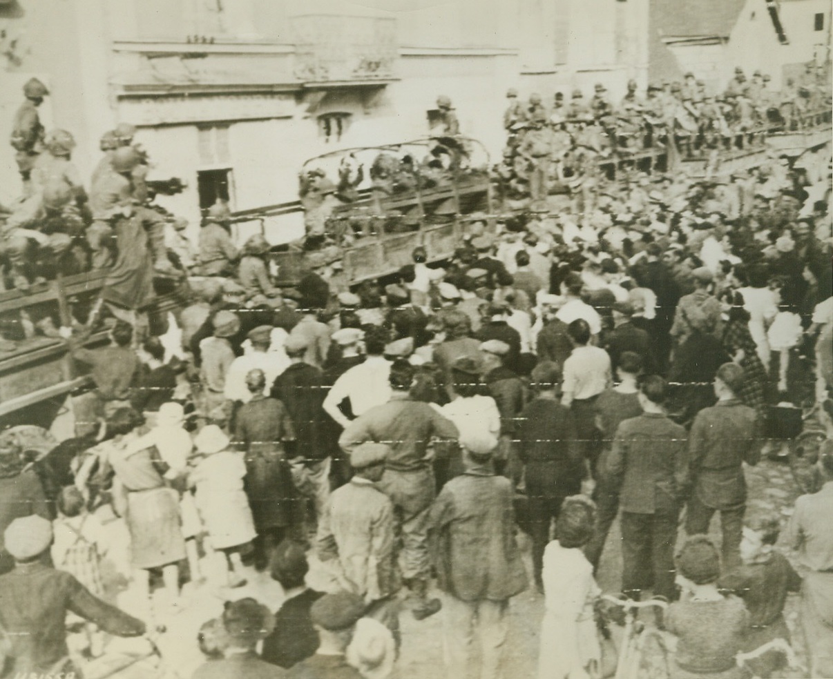 Nazi Prisoners Ride Yank Trucks, 8/15/1944. France—As residents stand at the side of the road, some of the 800 Nazis captured in Chateauneuf sur Sartre are driven by American soldiers on trucks to prison compounds.  Credit: Army radiotelephoto from ACME;