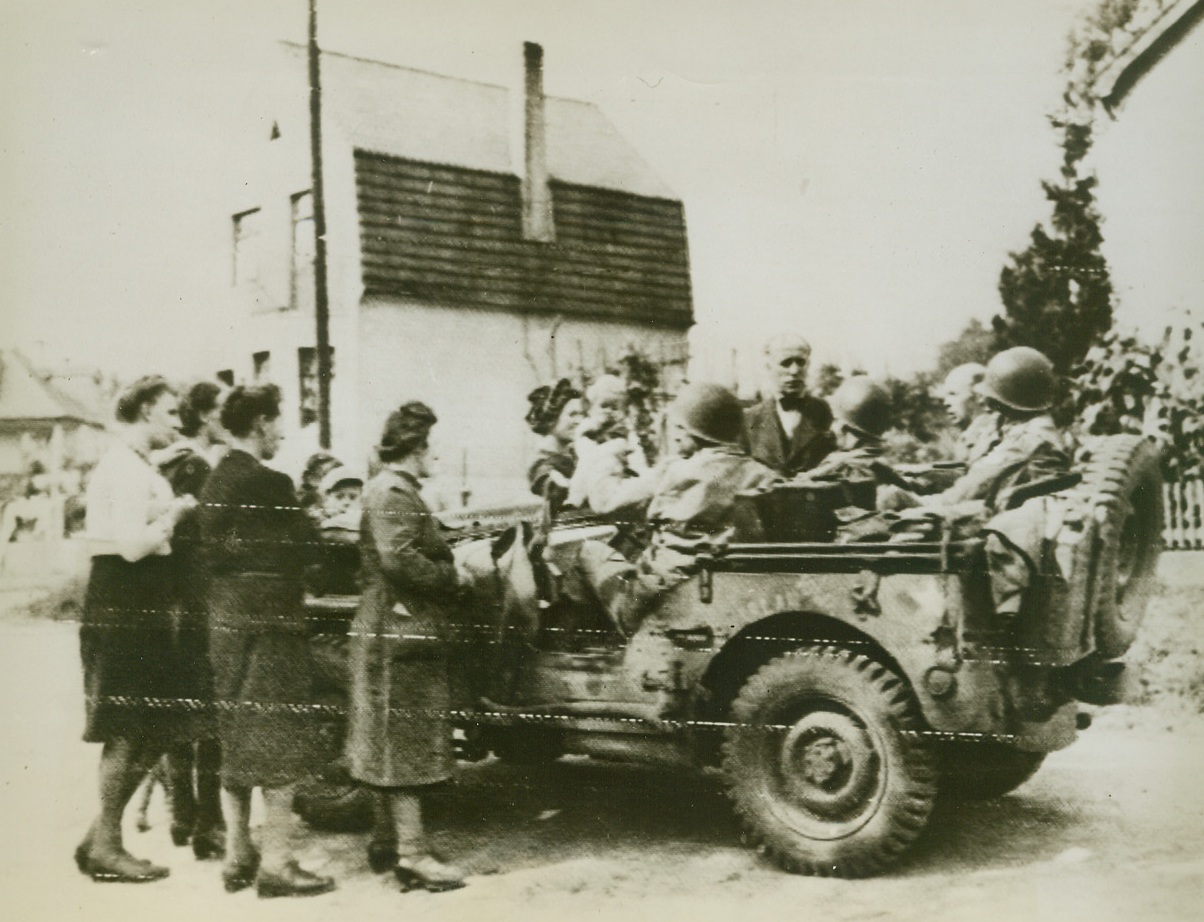 Germans Greet Yanks Near Aachen, 9/16/1944. GERMANY – A large German family residing near the key city of Aachen, Gathers around an American jeep which was part of the first column to enter Germany.  Civilians seem rather pleased to greet these soldiers of General Bradley’s First Army.Credit:  Andrew Lopez for War Picture Pool (Army Radiotelephoto from ACME);