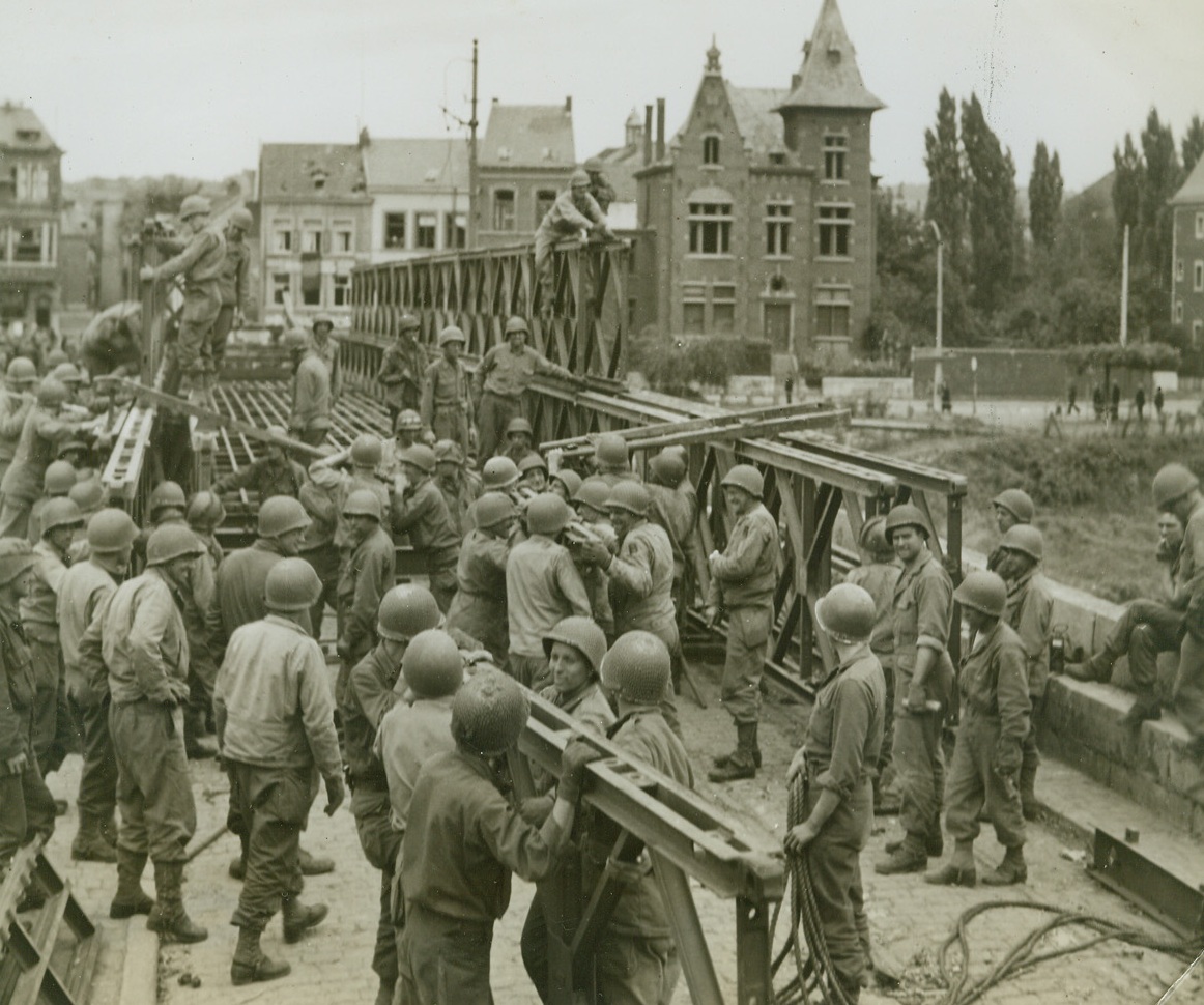 Yanks Span the Meuse, 9/12/1944. BELGIUM—American engineers and advance elements work hard to complete a bridge spanning the River Meuse in Namur, Belgium, in preparation for the crossing of armored columns. Photo by Andrew Lopez, ACME photographer for the War Picture Pool. Credit: ACME.;