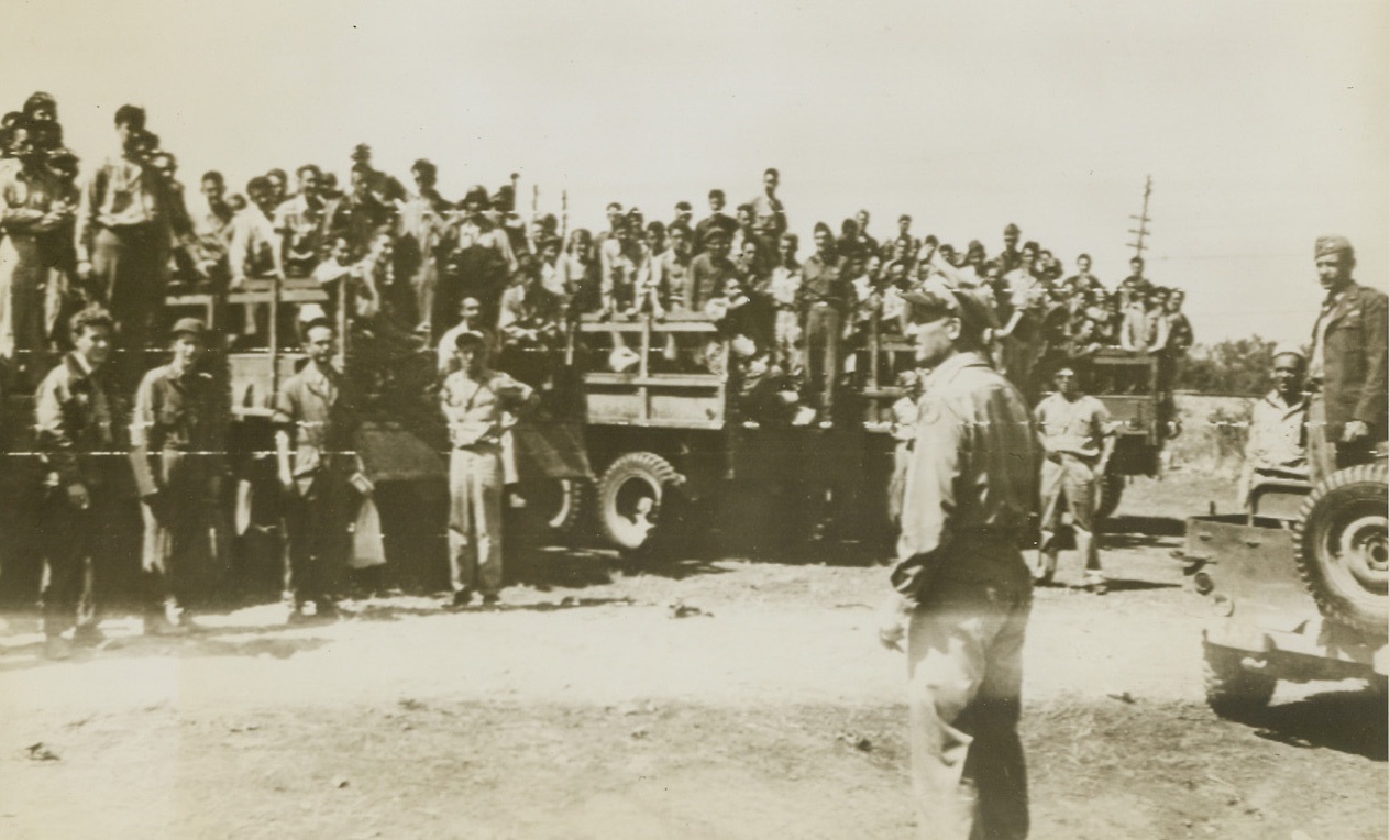 YANKS RETURNED FROM ROMANIA, 9/2/1944. ITALY—General Nathan F. Twining, Commanding General of the 15 Air Force, addresses a group of men who had just landed in Italy after being flown from Romania where they were interned as prisoners of war. The Yanks, all fliers, had been shot down during raids on the Ploesti oil fields.Credit: Army Radiotelephoto from Acme;