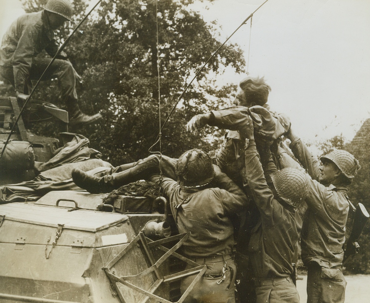 WOUNDED NAZI GETS A LIFT, 9/12/1944. BELGIUM—A wounded German prisoner is hoisted to an American armored car by a group of GI’s. He will be taken to a field hospital for treatment. Nazi was wounded during fighting in Belgium.Credit: Signal Corps photo from Acme;