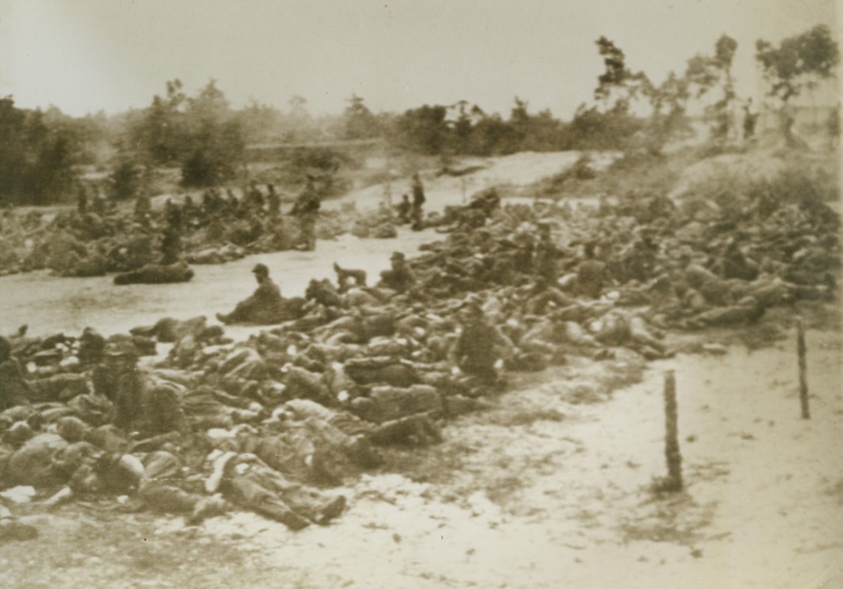 GERMAN PRISONERS IN HOLLAND, 9/26/1944. These Nazis were captured by Allied forces in the area of Nijmegen, Holland. Most of them were caught by parachutists. Here, they lie around on the ground, resting, as they await transportation to prisoner of war camps. Credit: British official photo via U.S. Army radiotelephoto from Acme;