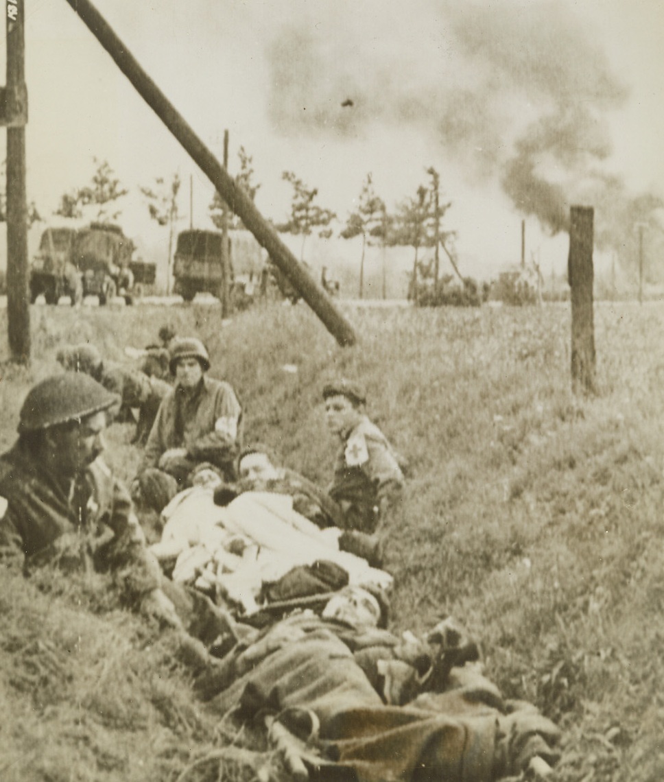 BRITISH WOUNDED TAKE COVER IN HOLLAND, 9/25/1944. HOLLAND—When their convoy, enroute from Eindhoven to Nijmegan was attacked by the Germans, these wounded British soldiers take cover in a slope in the ground. Tanks and typhoons soon drove off the attackers, and the convoy proceeded on its way. Credit: Signal Corps radiotelephoto from Acme;