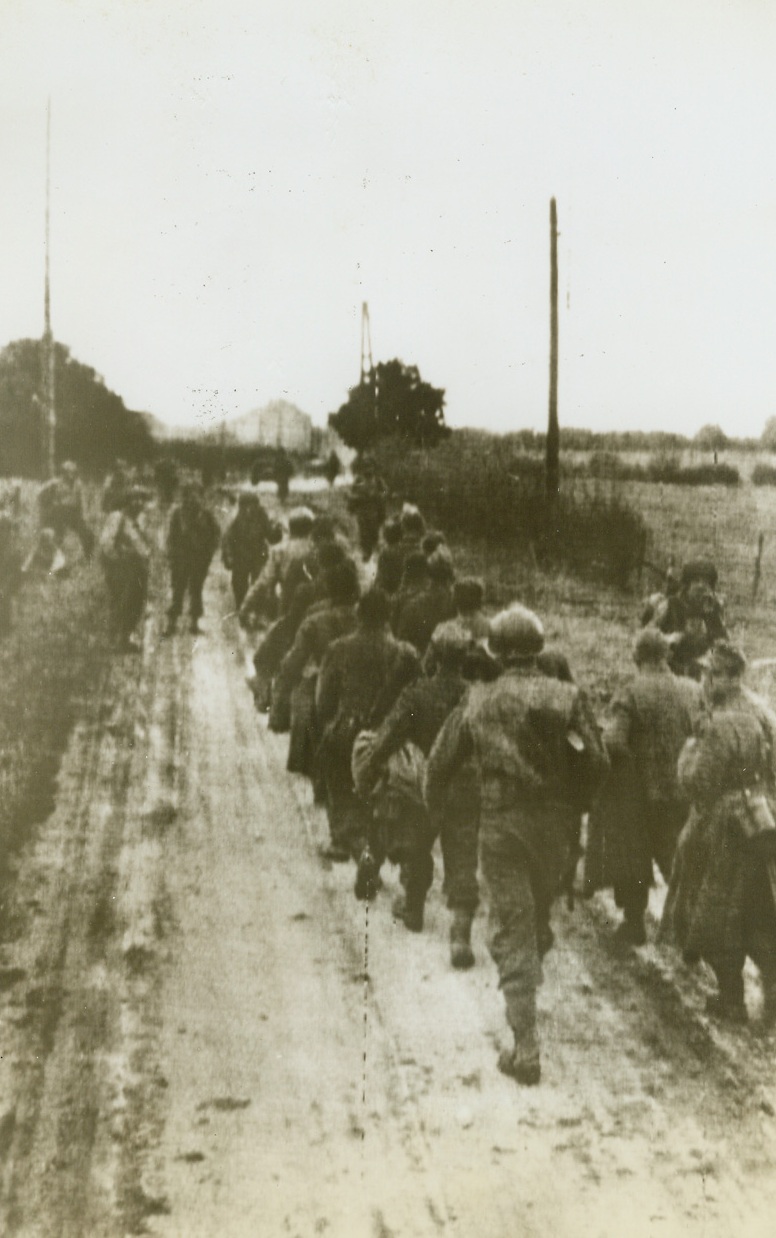 Prisoners in Their Homeland, 9/17/1944. AACHEN SECTOR, GERMANY – Charged to defend the mighty Siegfried Line at any cost, these German soldiers were taken prisoner in the Aachen sector. As they are marched toward the rear, they pass American infantrymen on their way to the front. This photo was made by Andrew Lopez, Acme photographer, for the War Picture Pool. Credit: (ACME) Photo via Army Radiotelephoto;