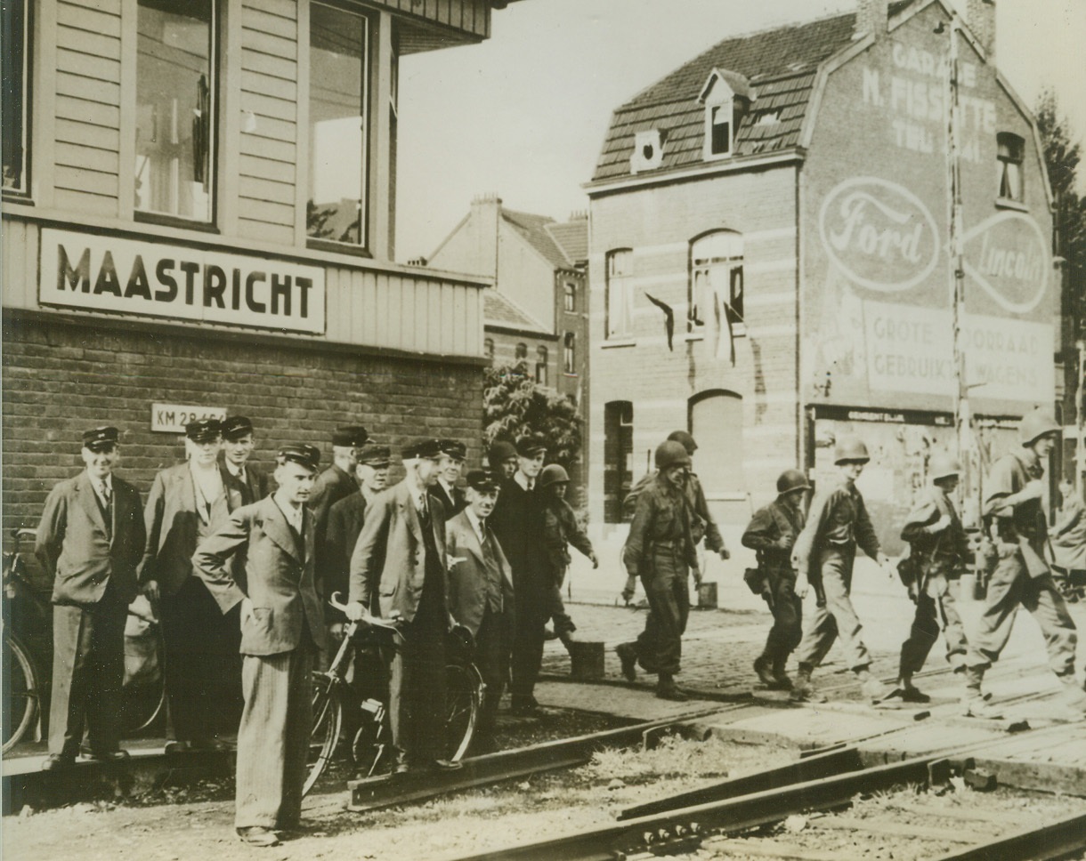 Yanks Tramp Thru First Free Dutch City, 9/22/1944. MAASTRICHT, HOLLAND – Smiling citizens of the ancient Dutch city of Maastrict, the first of Holland’s cities to be liberated by the Allies, watch American soldiers tramping across the local railroad tracks. First Army units, under the command of General Hodges, entered the city on September 14th.Credit Line – WP – (Acme);