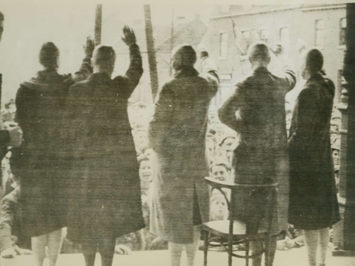 The Price of Collaboration, 9/19/1944. BELGIUM – Belgian women, their heads shaved bare, paid the price of their collaboration with the Germans during their Occupation of Lanaken. For good measure they are forced to give the hated Nazi salute before crowds of jeering countrymen.Credit (Army Radiotelephoto from Acme);