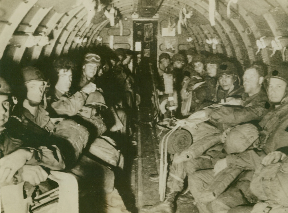 They’re Off!, 9/18/1944. EN ROUTE TO HOLLAND – Looking tough enough to star in a Nazi nightmare, each man heavily laden with equipment, officers and men line the sides of a C-47 and wait to reach their destination. All members of the First Allied Airborne Army, the fighters dropped to Dutch soil to confuse and trap thousands of German soldiers.Credit (Signal Corps Radiotelephoto from Acme);