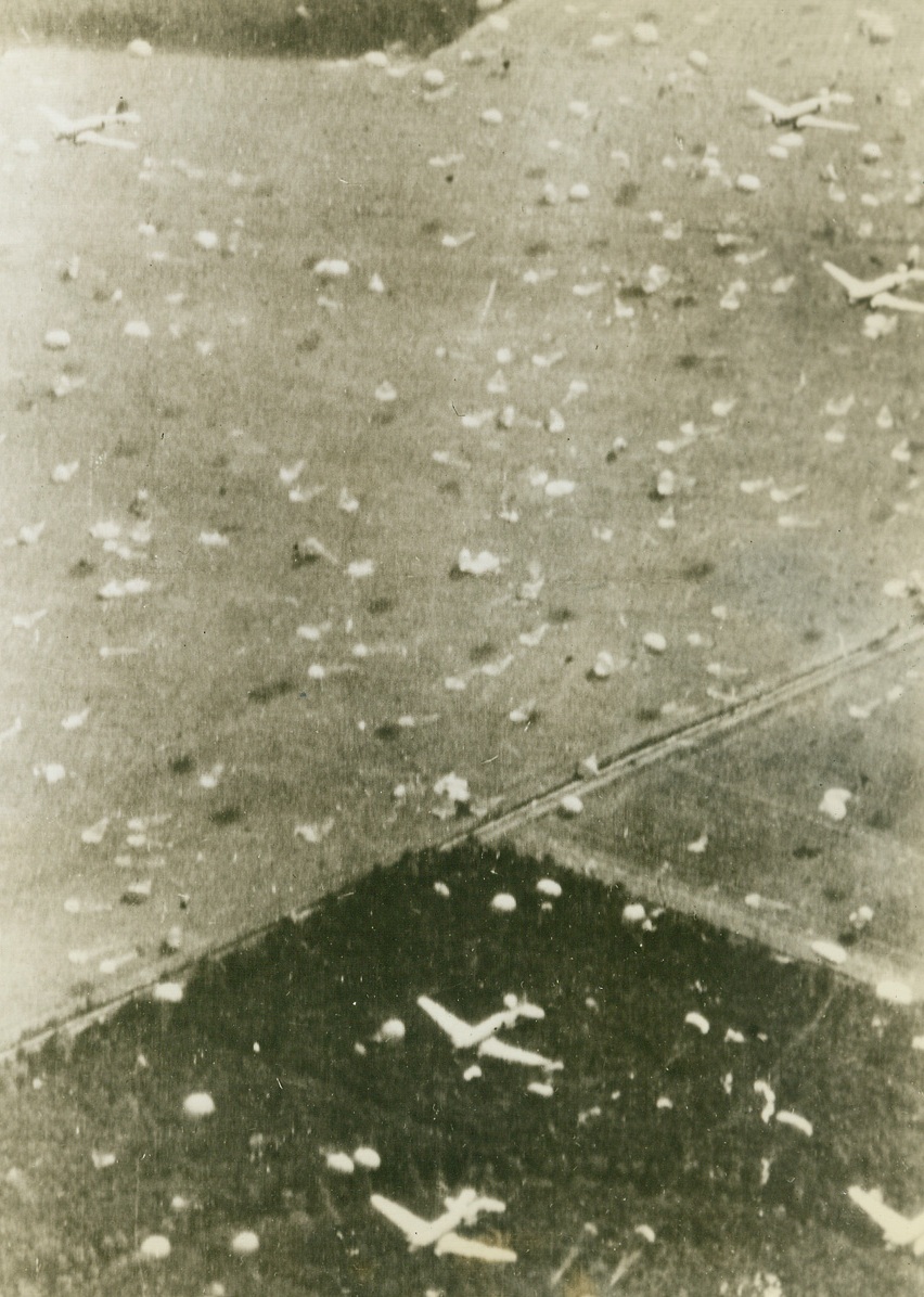 Invaders ‘Chute Down in Holland, 9/19/1944. HOLLAND – Parachutes fill the air as Allied aircraft drop more troops and supplies over Holland. The ground is still sprinkled with parachutes and gliders from the first day’s operations.Credit (British Official Photo via Army Radiotelephoto from Acme);