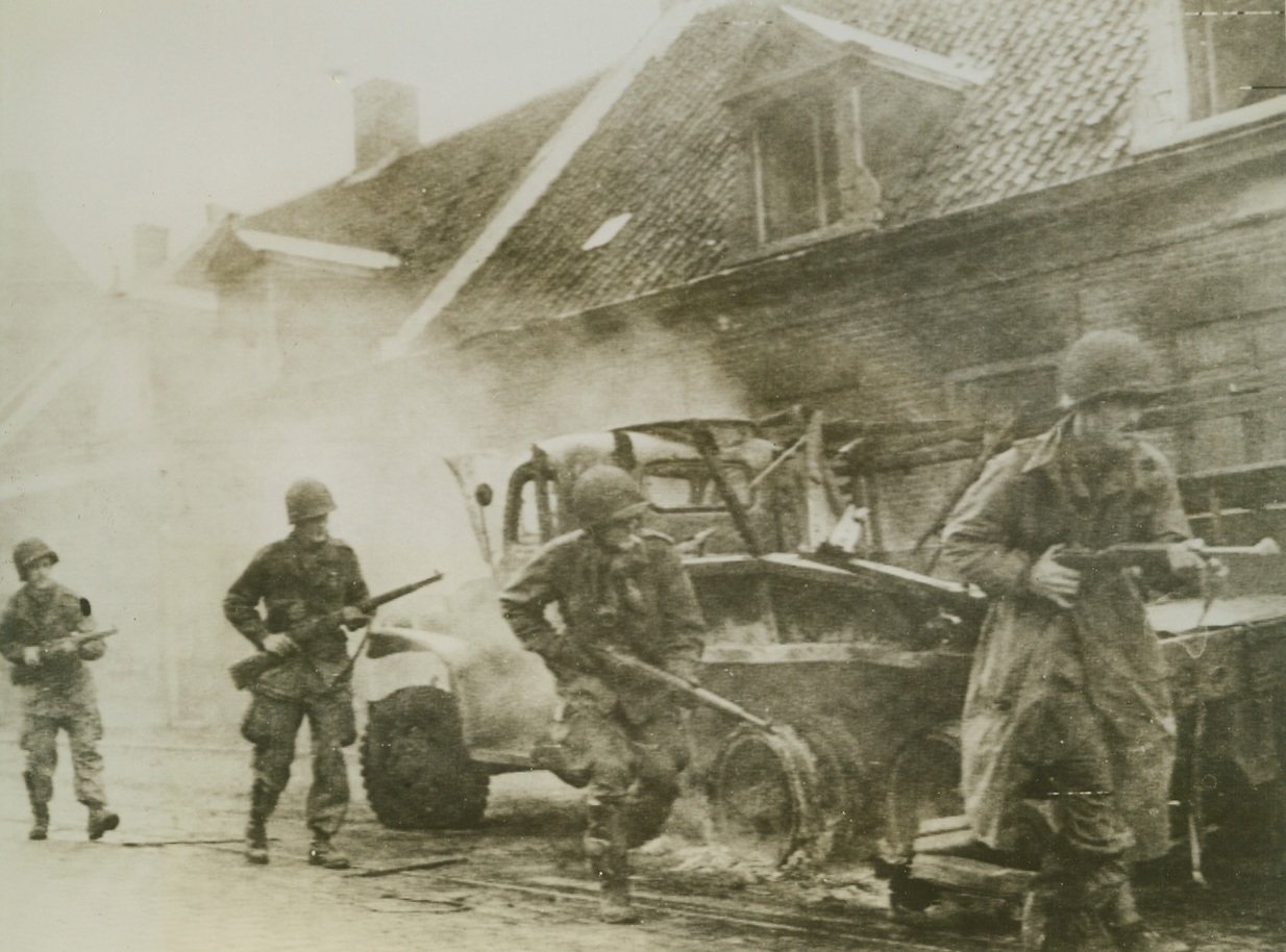 Airborne Infantry Advances in Holland, 9/29/1944. HOLLAND – With guns ready, US Airborne infantry advance cautiously along a street in Holland, moving though a haze of rifle fire, as they pass a burning truck while routing out snipers still lurking in the town.Credit ( Signal Corps Radiotelephoto from Acme);