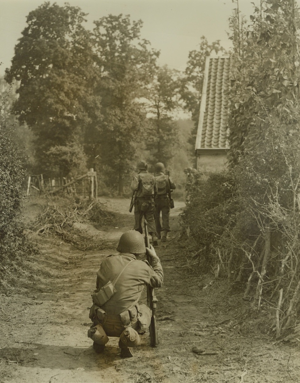 Over the Border, 9/18/1944. GERMANY -- There's no difference in soil, dust, on foliage from one end of this country lane to the other, but the steps that carried the Yanks in background down the path took them into Germany. Squatting behind them, a buddy watches the boys cross the border near Aachen. "Boy, this is what I walked across France and Belgium to see," he said. Credit: - WP- (Photo by Bert Brandt of ACME, for the War Picture Pool);