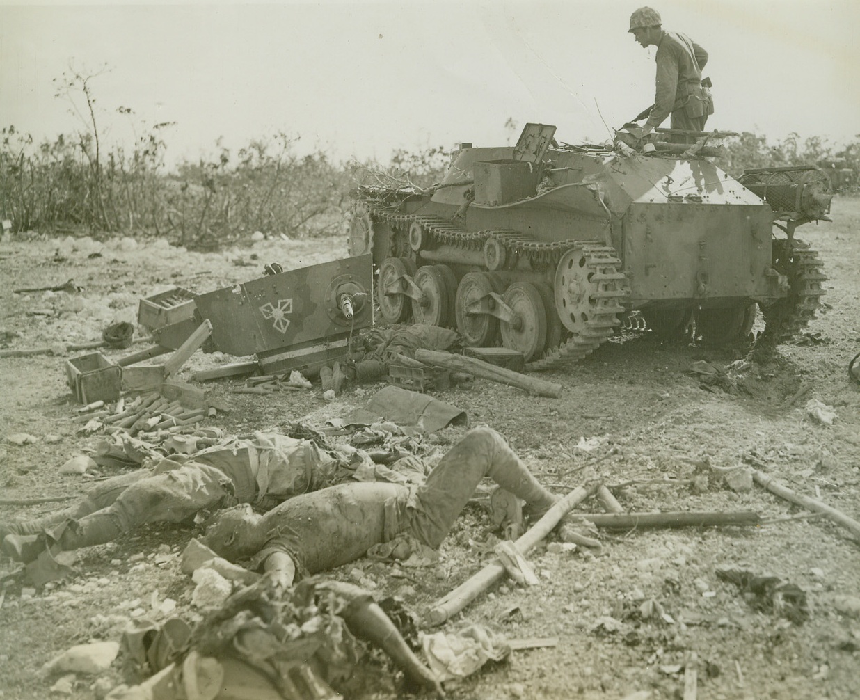 JAP TANKMEN SLAIN IN BLOODY ARMOR BATTLE, 9/24/1944. PELELIU ISLAND—These dead Japs sprawl before their tank, knocked out of the war forever by accurate shooting of Marine tankmen near Peleliu airport. Eight out of 12 enemy tanks were blasted to bits by one Leatherneck turret gunner, Corp. Edward Brooks of Washington, D.C. Here an alert Marine peers into inside of tank to make sure no survivors are hiding. Photo by Stanley Troutman, Acme Newspictures staff photographer for War Picture Pool. Credit Line (ACME);