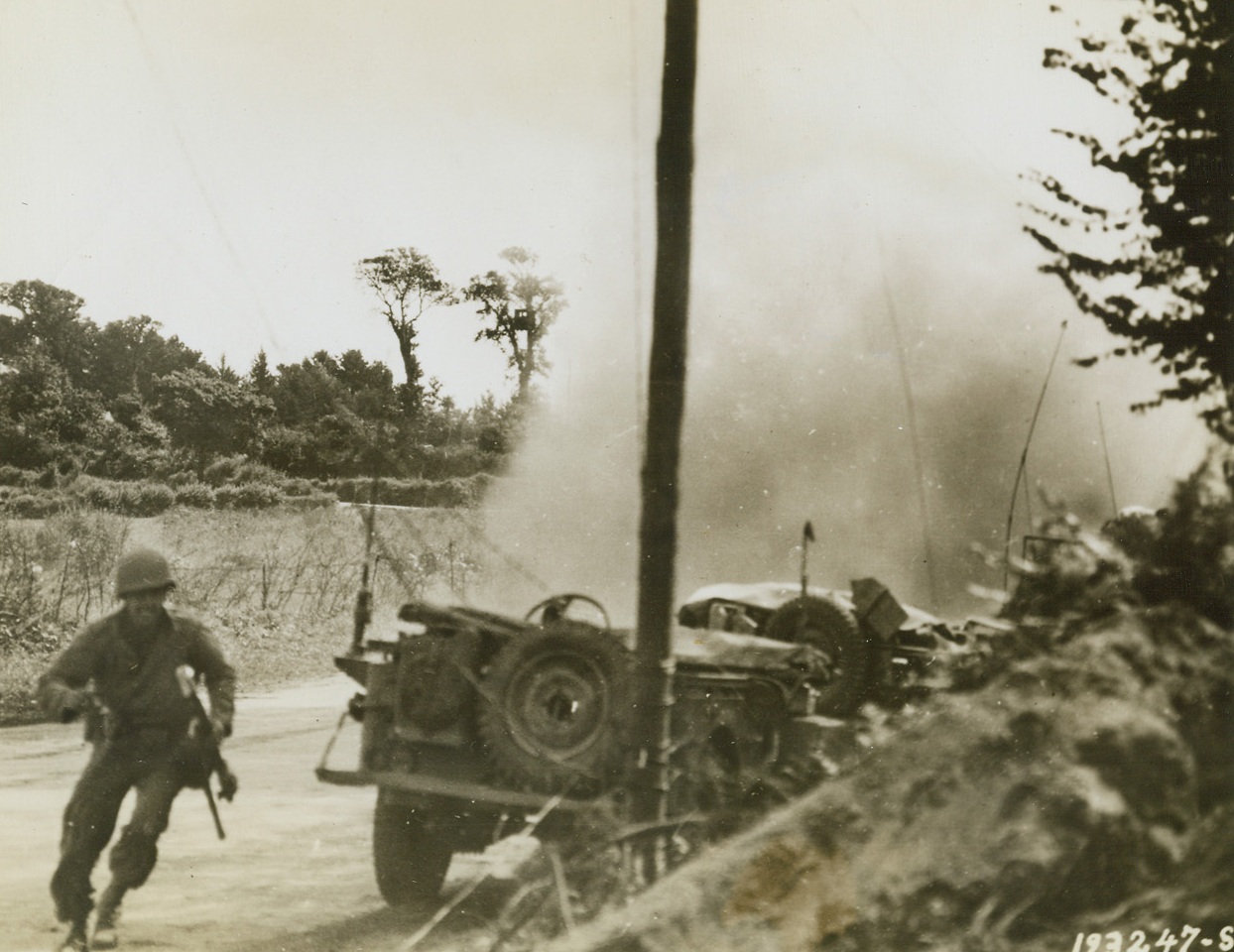 YANK INFANTRY COLUMN ENEMY TARGET, 9/5/1944. FRANCE – An American soldier dashes for cover as vehicles of U.S. column become target for Nazi guns in Brest, France. Smoke from near or direct hits on the column fills the area.Credit: Signal Corps photo from Acme;