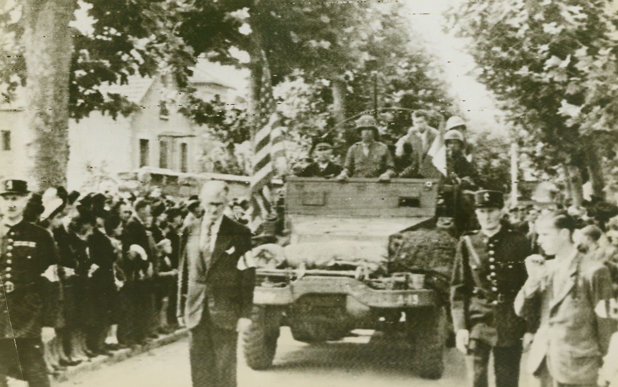 FUNERAL FOR FRENCH PATRIOTS, 9/1/1944. FRANCE – An American armored vehicle leads the funeral procession for twenty-seven French Maquis who were executed en masse by the Germans in St. Pol De Leon.  The victims’ eagerness to free their beloved homeland led them to attack the German garrison prematurely, and thus meet their death.Credit: Signal Corps radio telephoto from Acme);