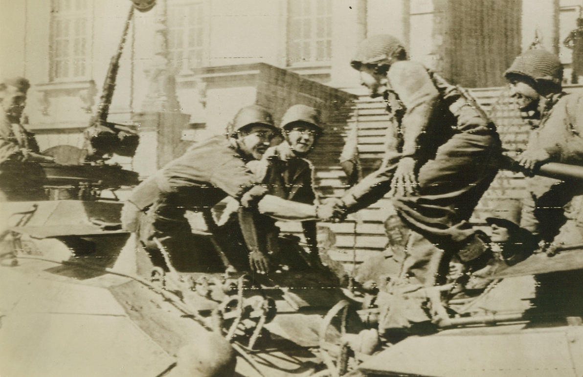 Allied Armies Meet in France, 9/16/1944. Army, leans out of his tank to greet Cpl. Carl Newman of Gen. Patton’s 3rd Army as the two Allied Forces meet somewhere in France. Newman is a Brooklyn boy. Credit: Army Radiotelephoto;