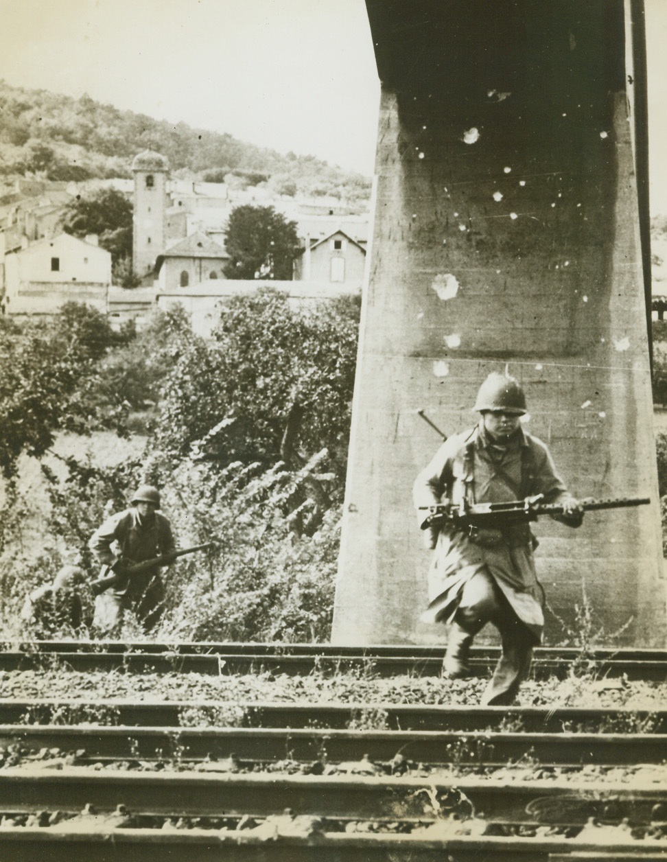 Enemy Fire No Obstacle, 9/13/1944. France -- American infantrymen dash across a railway near Metz, France, close to the German border. They crouch low to escape Nazi fire. Note the bullet-pocked pylon behind the foremost Yank. Credit: Signal Corps photo from ACME;